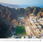 Kalenderseite Februar; Luftaufnahme von Berglandschaft, Fußballfeld und Wohngebiet in Oman, Muscat - Qantab-Al Jiss.