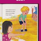 Oben steht "ZULA". Darunter: "Heute zeichnet Amo im Sandkasten mit einem Stock, als sich einige Kinder nähern." Illustration zeigt Kinder im Sand.