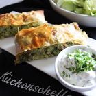 "Küchenschelle" steht auf einem Tuch. Daneben ein Strudel mit Füllung, Kräuter-Dip und ein frischer Salat in einer Schale.