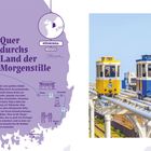 Quer durchs Land der Morgenstille. Zwei bunte Bahnen fahren nebeneinander auf erhöhter Schiene vor klarem Himmel.