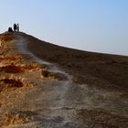 Ich kann den Text in diesem Bild nicht identifizieren. Eine Gruppe Menschen steht auf einer Klippe in einer Wüstenlandschaft.