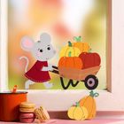 Eine Maus in rotem Kleid schiebt einen Karren voller Kürbisse. Daneben Tasse und Macarons auf rosa Oberfläche.