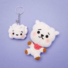 Ein gehäkelter Schlüsselanhänger mit Augen und Lächeln sowie eine größere, passende gehäkelte Figur daneben.