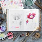 Notizbuch mit Skizzen und Aquarellen von Mohnblumen, Pinsel, Farben, Zeichnungen und Naturmaterialien auf einem Tisch.