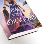 Der Text "WHEN DEALING WITH DRAGONS" und "DRACHENGOLD" ist auf einem Buchcover mit einer Person in einem violetten Kleid und mehreren Drachen zu sehen.