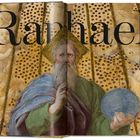 "Raphael" steht groß über einem Gemälde, das einen bärtigen Mann mit Heiligenschein zeigt.