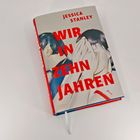 Auf dem Buchcover steht "WIR IN ZEHN JAHREN" in Rot. Zwei gezeichnete Personen bedecken ihre Gesichter mit den Händen.