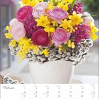 Kalendermonat: Februar. Blumengesteck in einem Topf mit gelben Narzissen und rosa Ranunkeln.
