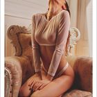 Text: "Februar" und ein Kalender von Februar 2025. Frau in durchscheinendem Oberteil kniet auf einem Sessel.