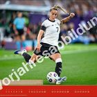 "Vorjahresabbildung" diagonal, weißer Text. Fußballerin im weißen Trikot in Aktion, dynamische Pose, grüner Platz, roter Kalenderstreifen.