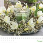 Kalender mit Februar unten, weiß-gelbe Blumen und grüne Kerze in der Mitte.