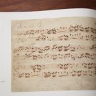 "Inventio 8" ist in geschwungener Schrift oben auf einer Seite mit Notenzeilen geschrieben. Hintergrund ist braun und papierartig.