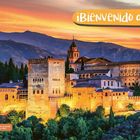¡Bienvenido a España! Die Alhambra, eine Festung in Granada, vor einem malerischen Sonnenuntergang und Bergen.
