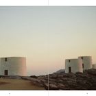 Seitenzahlen 74 und 75. Drei runde weiße Gebäude auf felsiger Landschaft bei Sonnenuntergang.