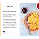 "Pancakes" wird in der Mitte beschrieben. Links Rezeptzutaten. Rechts ein Teller mit goldgelben Pfannkuchen und Ahornsirup.