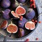 Kalender mit Tagen 1-28. 
Violette Feigen, einige halbiert, auf einem Tablett mit roten Beeren.