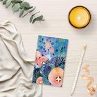 Text "2027" auf einem Notizbuch mit bunten Blumenmustern. Daneben ein Stift, eine Kerze und ein Zweig.