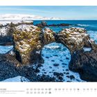 02 ISLAND: Felsformation vor Arnastapi. Schneebedeckte Felsen mit natürlichem Torbogen, dahinter das blaue Meer.