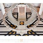 Eine geschwungene Treppe im Museum für Islamische Kunst in Doha, Katar, umgeben von geometrischen Mustern am Boden.