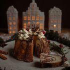 Ein dekorativer Kuchen mit Sahnehaube, Zimt und Anissternen. Hintergrund: erleuchtete Porzellan-Häuser.