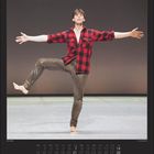 Februar. Tänzer hebt ein Bein, trägt rot-schwarz kariertes Hemd, gestreckt im Raum. Kalender darunter zeigt Monatsdaten.