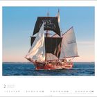 Ein Segelschiff mit schwarzen Segeln, ein Hund ist auf dem Hauptsegel abgebildet. Unten steht "2 2027".