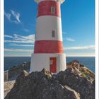 Kalenderblatt für Februar 2027. Foto: Leuchtturm Cape Palliser, Neuseeland. Roter und weißer Turm, blauer Himmel.