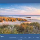 Februar 2027. Kalenderseite. Sandstrand mit Booten und Gräsern bei Sonnenuntergang.