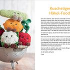 „Kuscheliges Häkel-Food!“ steht neben einem Bild mit niedlichen, gehäkelten Obst- und Gemüsefiguren in einem Metallsieb.