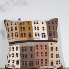 Strickkissen mit Stadtmuster in beige, braun und gelb. Zwei kleine Taubenfiguren auf den Ecken.