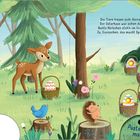 Text: "Die Tiere freuen sich: Hurra! Der Osterhase war schon da. Bunte Körbchen steh’n im Gras. Ja, Eiersuchen, das macht Spaß!" Eine Illustration zeigt Tiere im Wald mit Osterkörbchen und Eiern. Ein Bär und ein Waschbär schauen hinter Bäumen hervor, ein Reh steht da und ein Vogel und ein Igel sitzen auf Baumstümpfen.