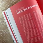 "WO IST DIE ABKÜRZUNG ZUR FREUDE?" steht groß auf rotem Hintergrund geschrieben. Eine Buchseite mit Text.