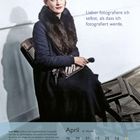 „Lieber fotografiere ich selbst, als dass ich fotografiert werde.“ Frau mit schwarzem Hut und Fellkragen sitzt auf einem Stuhl.