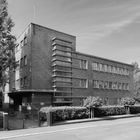 Hausnummer 42-47 ist an einem modernen Backsteingebäude angebracht, umgeben von Bäumen und einem Zaun.