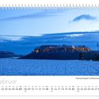 „Februar“, „Festung Königstein zur Blauen Stunde“. Winterlandschaft mit beleuchteter Festung und schneebedecktem Feld.