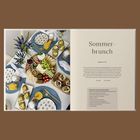 "Sommerbrunch. Greek Style. Die perfekte Vorbereitungs-Reihenfolge. Personen: 4. 2-3 Stunden."  

Ein gedeckter Tisch mit Speisen.