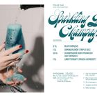 "Sparkling Blue Champagne", Zutaten: Blue Curaçao, Orangenlikör, Champagner, Limettensaft. Bild: Hand hält schäumendes Getränk.