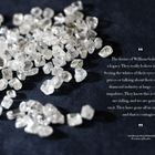 Ein Zitat über die Tradition und Hingabe an Diamanten, daneben ungeschliffene Diamanten auf dunkelblauem Stoff.
