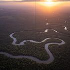 Keine sichtbaren Texte. Eine Flusslandschaft in der Dämmerung, mit sich windendem Fluss und bewaldeten Ufern im Sonnenuntergang.