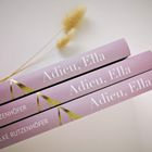 Drei rosa Buchrücken mit „Adieu, Ella“ und „ELKE RUTZENHÖFER“. Daneben liegt ein dünner, heller Zweig.