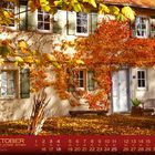 „OKTOBER“ Kalenderblatt mit Daten unten. Haus mit herbstlichen Blättern bedeckt, vier Fenster, Sitzbank vor der Tür.