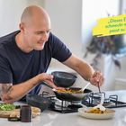 „Dieses Essen schmeckt mir und passt zu mir.“ Ein Mann kocht in einer modernen Küche und richtet Essen an.