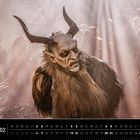 Kalender mit Monat Februar. Eine Person in einem traditionellen, dämonischen Kostüm mit Hörnern und Pelz inmitten von Rauch.