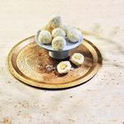 Drei Fleischspieße auf einem flachen Brot, garniert mit Kräutern und Joghurt, angerichtet auf einem goldenen Teller.