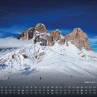 Kalender mit Daten 1-28, Monatsüberschrift "Sellamassiv, Dolomiten". Schneebedeckte Berge unter blauem Himmel.