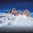 Sellamassiv, Dolomiten, Kalender unten mit Tagen und Daten. Schneebedeckte Berge unter blauem Himmel. Skifahrer im Vordergrund.