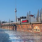 Kalender mit Zahlen für den Monat Februar. Zug auf einer Brücke, dahinter der Berliner Fernsehturm.