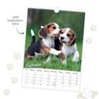"100% Niedlichkeitsfaktor" und "September". Zwei spielende Welpen auf grünem Gras, Kalender für September.