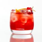 Ein Glas mit rotem Getränk, Eiswürfeln, Orangenscheibe und roten Beeren, auf weißem Hintergrund.