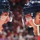 Auf den Helmen steht "VISIT LAUDERDALE". Zwei Eishockeyspieler brüllen sich an, tragen rote Trikots und Helme.